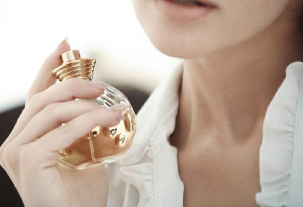 mulher segurando frasco de perfume